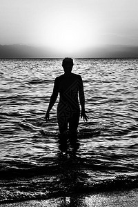 日落时在水上行走的年轻女子图片