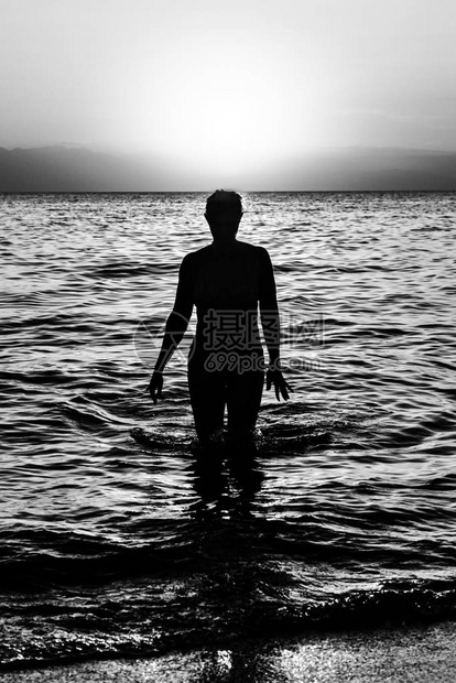 日落时在水上行走的年轻女子图片