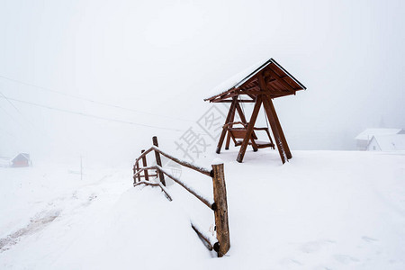 雾中雪山村的木栅栏和秋千图片