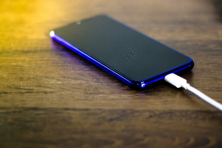 智能手机在木桌上给电池充电图片
