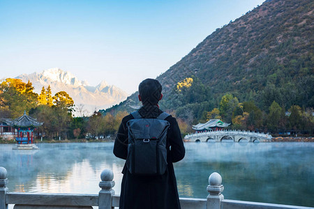 在玉龙雪山背景的黑龙池旅游的青年旅行者背景图片