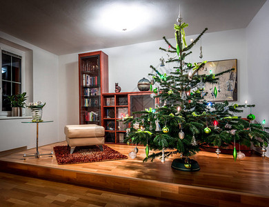 装饰丰富的圣诞树在一个冷酷的现代家庭图书馆里配有木图片