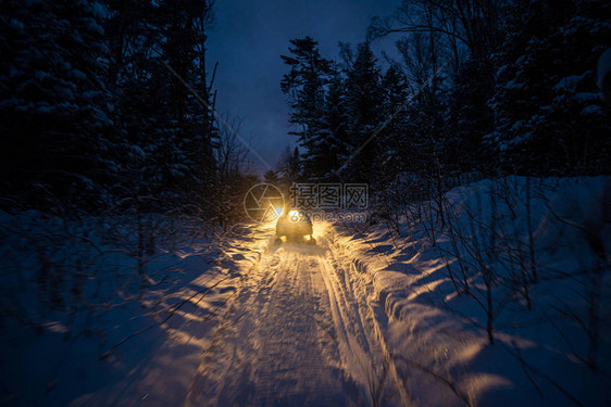 晚上的雪地摩托穿过冬季大灯穿过冬季的夜路雪图片