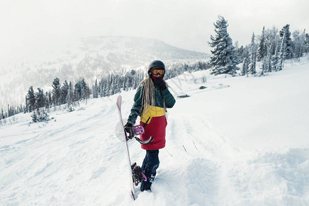 与滑雪板的女滑雪板在雪坡上的山图片