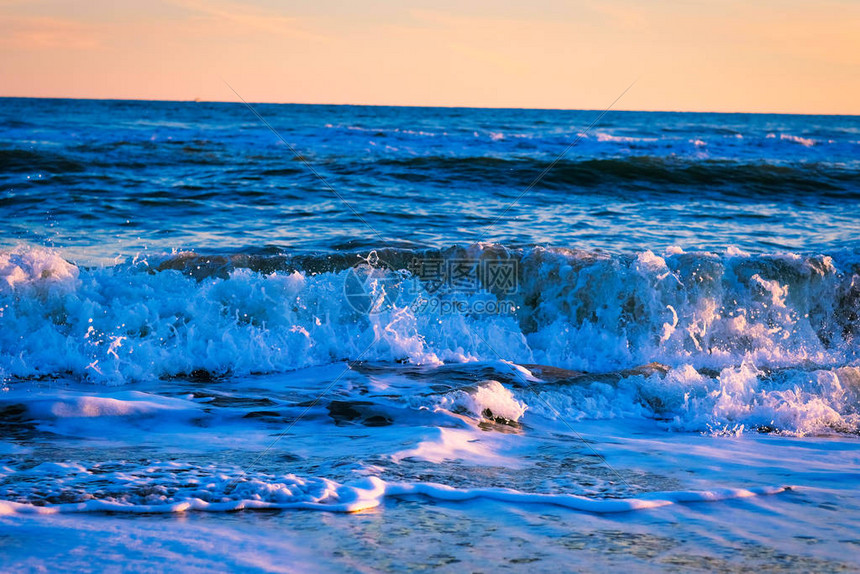 令人惊叹的海滩日落与令人难以置信的波光粼的海浪壮观的海滩上的日落和海浪蓝图片