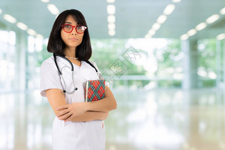 一名年轻女医生或身戴红眼镜的学生在医院大厅用文件夹折手站立图片