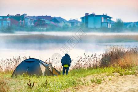 绿色帐篷和在河附近的一个男子晨雾图片