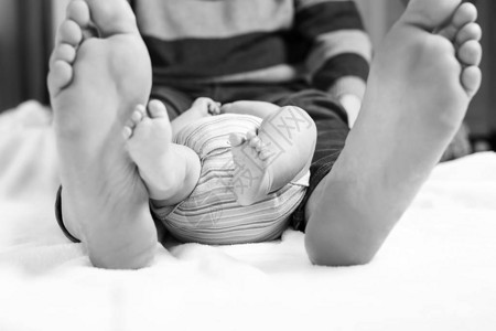 父亲和刚出生的小婴儿的大脚特写成人的大脚和孩子的小腿快乐的父母图片