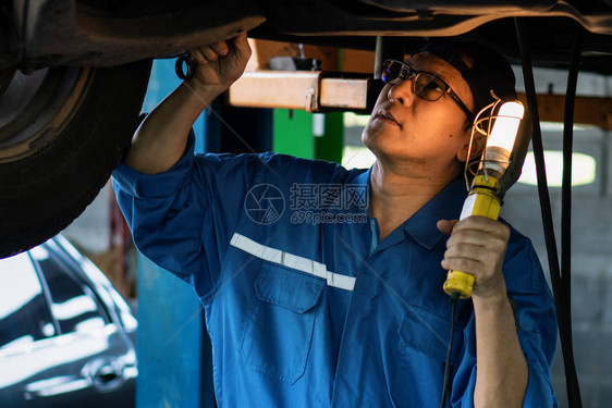 亚洲男汽车修理工在车库和汽车维修服务站进行汽车检查和维图片