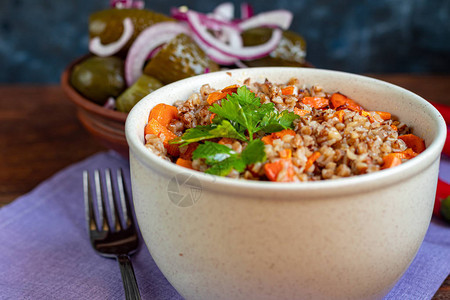 荞麦粥在一碗炖胡萝卜背景是发酵的腌黄瓜和红辣椒在一张棉质餐巾纸上图片