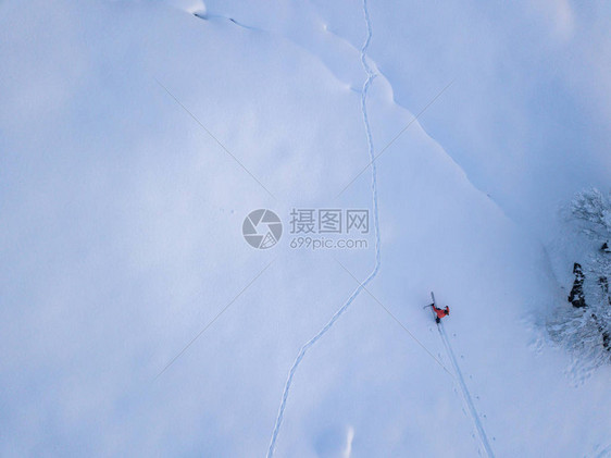 登山者在雪覆盖的偏远地区与旅游滑雪一起向上远足的鸟瞰图野图片