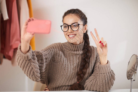 身戴眼镜的当代年轻女透过智能手机拍摄自相照片图片