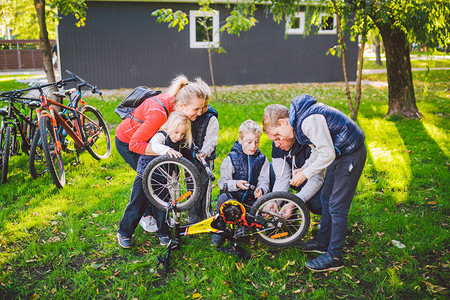 团队合作和友好家庭的主题户外运动父母教孩子如何解决问题父亲展示如何自己修理自行车在公园修图片