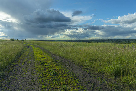 穿过田野的土路通往雷暴云图片