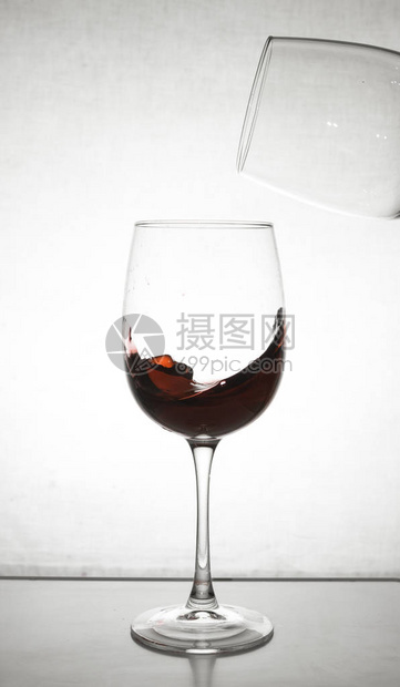 红酒从杯里飞溅出来上面的空杯子的一部分图片