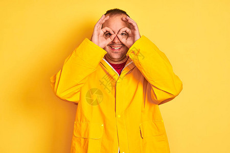 穿着雨衣的年轻人站在孤立的黄色背景上图片