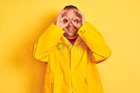 穿着雨衣的年轻人站在孤立的黄色背景上图片