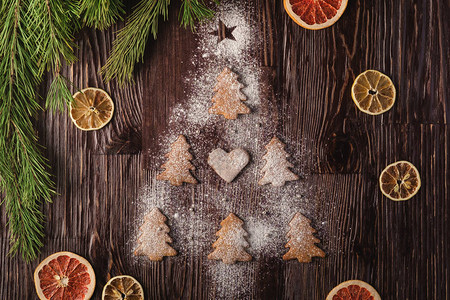 以圣诞firtree形状和木本底有糖粉的姜饼柑橘干果fir树图片