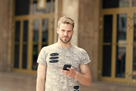 移动生活方式白种人在户外使用手机在城市街道上手持个人移动设备的帅哥时尚男人享受移动互联网的短图片