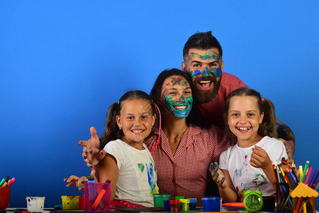 创造力和家庭观念父母和孩子的脸在蓝色背景上涂有水粉女孩图片