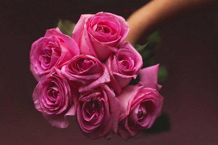 在黑暗背景下手握着美丽的粉红玫瑰花束情人节礼物图片