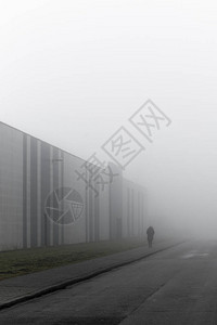 孤立的人走在雾蒙的工业道路上图片