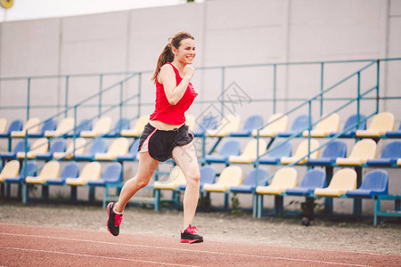 跑在体育场的妇女在体育场跑道上跑步的年轻女子目标成就概念在球场上进行健身慢跑锻炼健康主题减肥成功的运动图片