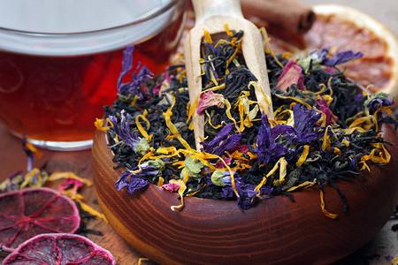 混合茶红茶干花瓣和柑橘类水果干红茶叶放在木勺和一杯新图片