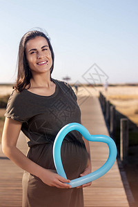 孕妇在沼泽地上拿着蓝色的心形气球合影图片