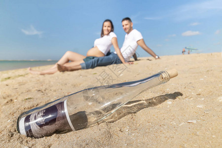 快乐的一对孕妇在海滩岸上摆姿势瓶子里图片