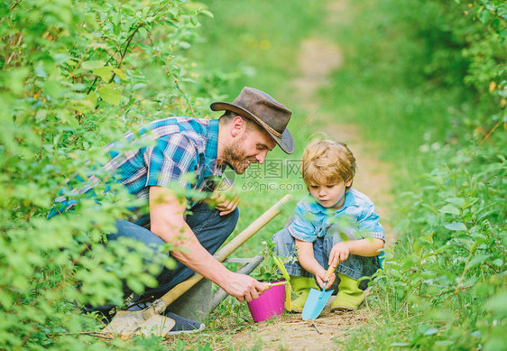 小男孩帮助父亲务农生态农场父亲和儿子在牧场上的牛仔帽锄头锅和铲子园林设备地球节快乐家图片