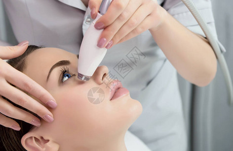 淋巴引流按摩液化石油气设备过程治疗师美容师在美容院为模特做面部按摩特写图片