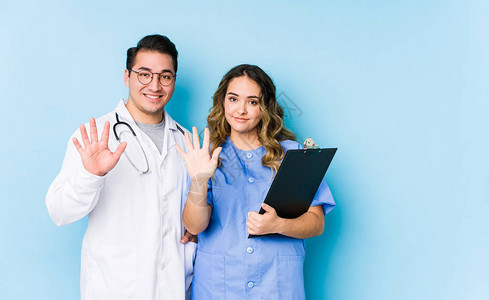 年轻医生夫妇在蓝色背景中装扮孤立地微笑着快乐的笑容展图片