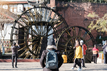 年轻女子旅行者在丽江古城的巨型水轮上旅行图片