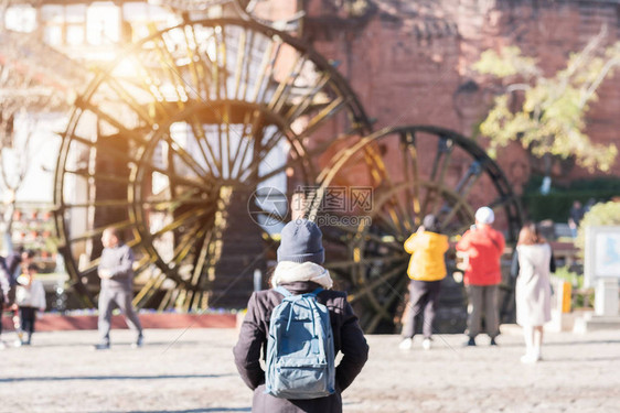 年轻女子旅行者在丽江古城的巨型水轮上旅行图片