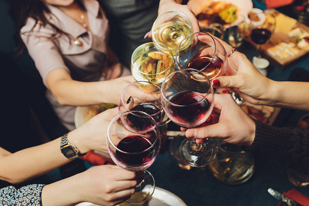 一群贴近镜头的人群在bokeh背景面前把杯子和葡萄酒或香槟连在一图片