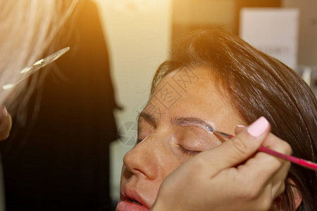美容师化妆师在美容院的矫正会议上在以前拔过设计修剪过的眉毛上涂指甲图片