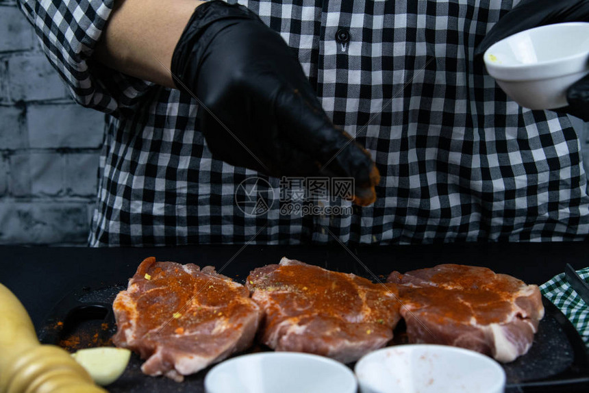 黑手套厨师洒着红胡椒鲜嫩的奶油新鲜生猪肉在木制图片