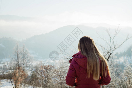 年轻女人在冬天看着山上图片