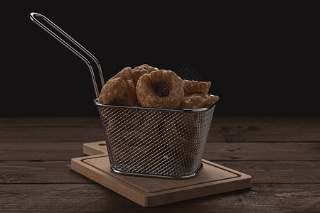 葱花灌饼在一个摊子和木制桌子上一个小金属篮子中一些猪皮灌液的背景