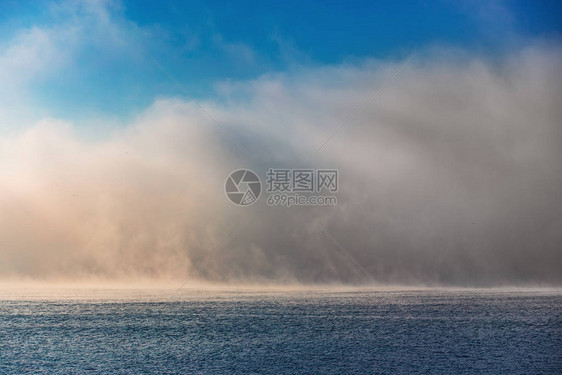海日出和雾的清晨蓝色波纹水上的图片