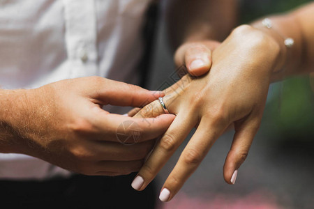 男人戴结婚戒指在女人手上关闭爱和承诺的象图片