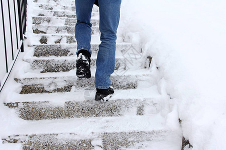 在冬天走上积雪的楼梯很危险一个男人在图片