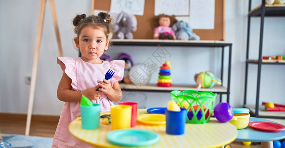 年轻漂亮的幼儿玩餐具和食品玩具游戏在客图片