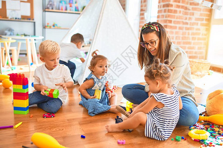 美丽的老师和一群幼童在幼儿园玩很多玩具图片