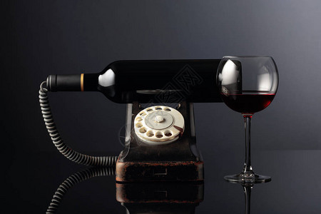 黑色反射背景的旧黑手机和红葡萄酒概念图像您可以自由使用图片