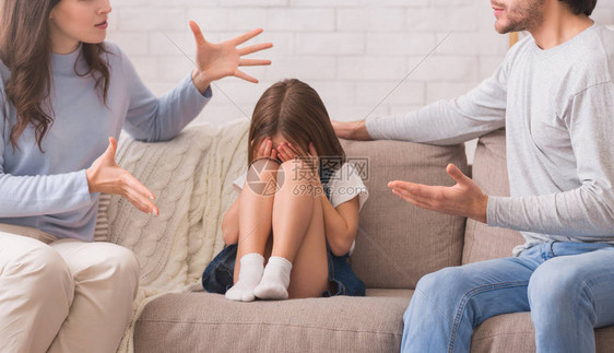 坐在父母争吵和哭泣之间的无辜小女孩图片