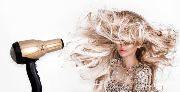 长而闪亮的卷发的金发女孩卷曲发型的美女模特吹干头发带吹风机的模图片