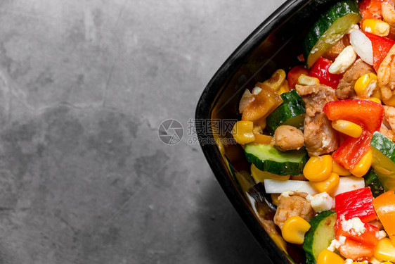 明亮的蔬菜沙拉配鸡肉灰色混凝土背景为健康饮食制作美味沙拉拍摄了一块黑盘子的特写图片