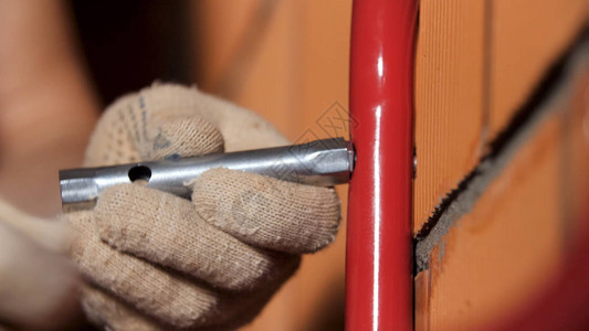 一位男工人在墙上工作时使用x扳手的近视大师试图将金属细节图片